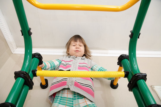 Children workout. Little girl on gymnastic bar. Child health care and physical development concept. Happy and healthy childhood. Kid on horizontal bar. Toddler screw up eyes being afriad of height.