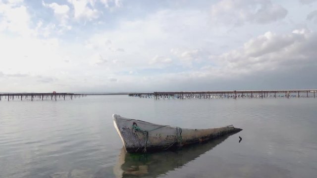 timelaps avec une &eacute;pave de barque &agrave; moiti&eacute; immerg&eacute;e dans un &eacute;tang et des nuages en mouvement