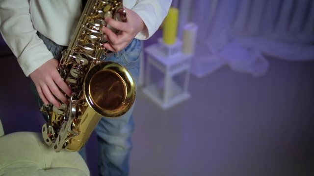 The boy plays the saxophone