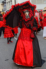 Fototapeta na wymiar Touloulou en noir et rouge sous son parapluie à la journée des diables rouges du carnaval de Cayenne en Guyane française 