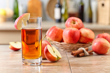 Glass of apple juice and ripe pink apples on a kitchen table