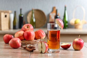 Glass of apple juice and ripe pink apples on a kitchen table