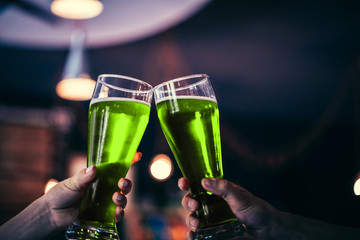 Two friends toasting with glasses of green beer at the pub with free space for your text. Beautiful...
