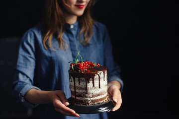 Chocolate cake with currants in the hands of the girls