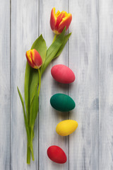 Easter concept with flower and decorative eggs over wooden background