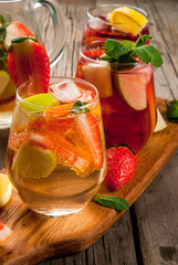 Traditional summer drink sangria - red, pink and white. With champagne, pink and red wine, strawberries, oranges, lemon, green apple and grapefruit. On a wooden rustic table, copy space 