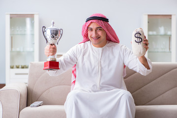 Arab man with prize and money on sofa