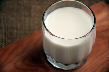 A glass of milk on wooden board on a background sacking, burlap,