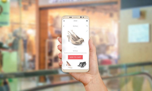 Shopping online with modern phone with round edges. Woman holding phone. Shop in background.