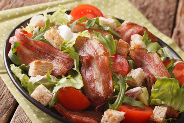 Spicy salad of bacon, tomato, croutons and lettuce close-up on a plate. Horizontal