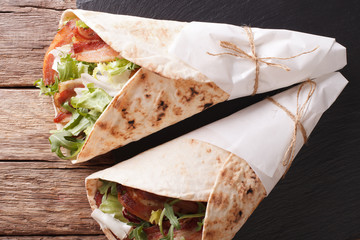 Fried bacon and salad wrapped in pita bread close-up on a table. horizontal top view