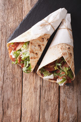 Burritos with bacon and fresh mix of salad close-up. Vertical top view