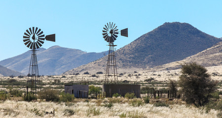 Two windmill water pumps in the heat haze on farm