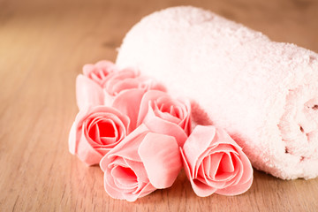 Мыло в виде роз и полотенце на деревянном фоне