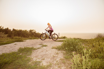 Fototapeta na wymiar Girl on mountain bike rides on the trail on a beautiful sunrise.