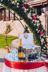 bottle of champagne and glasses on the table with box for gifts. Festive table. Outdoor.