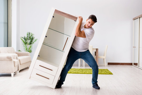 Young Man Moving Furniture At Home