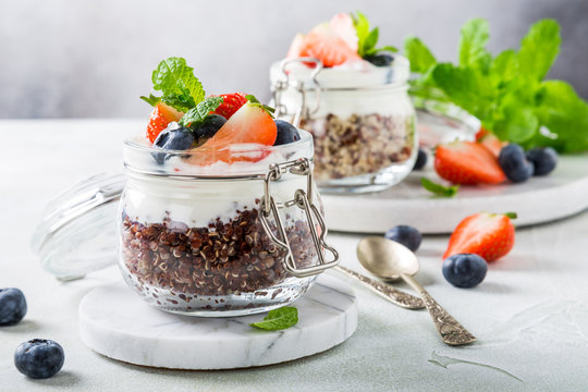 Gluten free breakfast with red quinoa, yogurt and berries in glass jar. Healthy super foods concept.