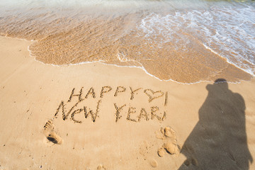 Happy New Year text on the sea beach.