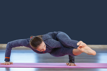 Young attractive woman practicing yoga, standing in Crane, Bakasana pose,