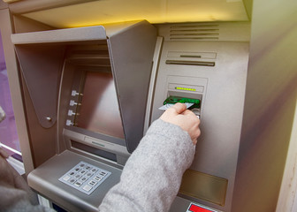 female hand put the card into the ATM