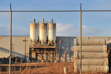 A manufacturing business secured behind a chain link fence, topped by barb wire in this industrial...
