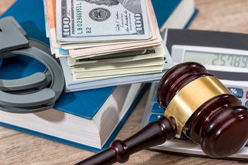 Law gavel with Dollars in book and handcuffs, close up.