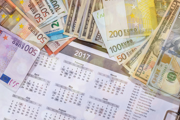 euro and dollar bills, calculator, ink pen and coin money on calendar background
