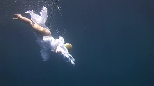 Young girl model free diver underwater white angel costume poses in Red Sea. Filming a movie. Extreme sport in marine landscape, coral reefs, ocean inhabitants. Free diver.