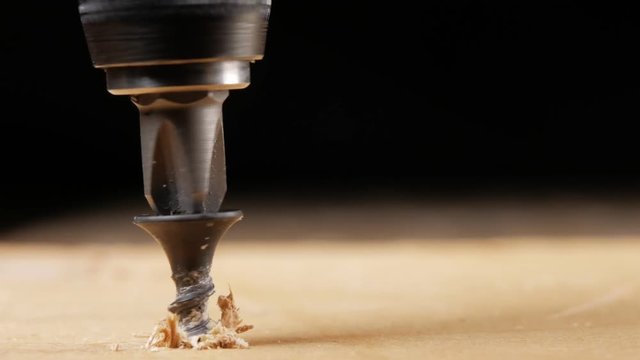 The screw is twisted by an electric drill in a wooden surface. Close-up of a moving camera. Visible microcracks tree