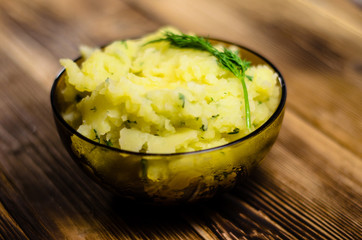 Mashed potatoes in glass bowl on wooden table