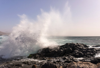 Fototapeta na wymiar vague se brisant sur les rochers