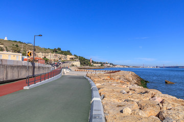 Fototapeta na wymiar Vista do Passeio maritimo em Oeiras com o Farol de Gibalta em Fundo