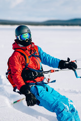 Fototapeta na wymiar Snowkiting. Male athlete snowboarder rides a kite skiing on a frozen lake. The Kola Peninsula. kiting. Snowkite