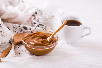 Bowl of homemade melted caramel sauce and coffee