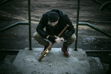 Dangerous young bad boy thug in the suburban area with baseball bat and brass knuckles