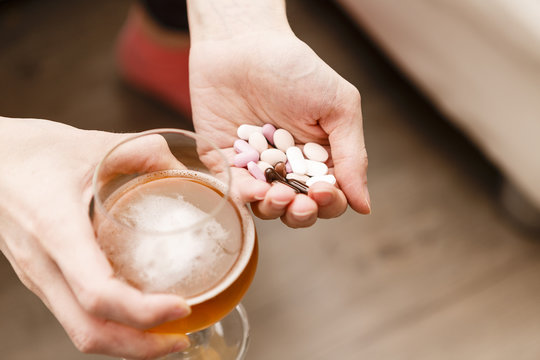 addict problem, woman with pills and beer in hands.