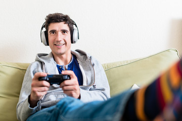 Happy young man playing a video game on console at home