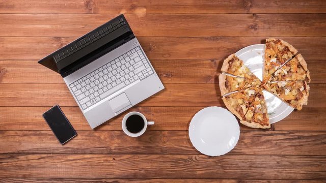 The plate takes a separate piece from the whole pizza. After the man is pizza and works for the laptop. Stop motion animation.