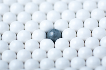 Black bulb among many white ones. Background of airsoft balls