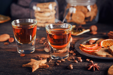 Whiskey or liqueur, cookies, spices and decorations on wooden background.