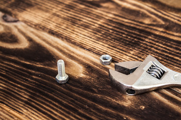 a wrench and a bolt with nut on wooden background