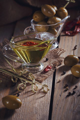 Premium extra virgin olive oil and green olives with fresh herbs, black pepper and chile pepper on...