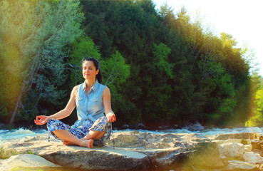 Woman meditating on the riverside. Woman enjoying and meditating in a beautiful environment. Its a beautiful sunny day, the air is full of positive energy!