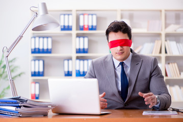 Blindfold businessman sitting at desk in office