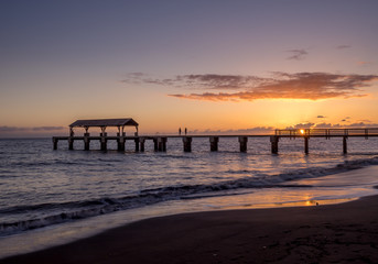 Fototapeta na wymiar Photo of Waimea Town pier at sunset taken with long exposure used to smooth and blur the ocean.