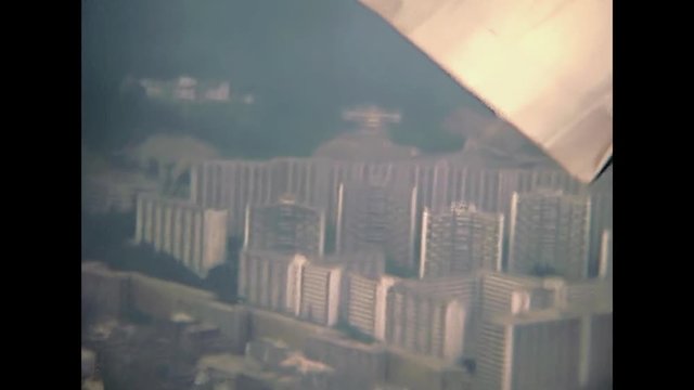 Point of view of a passenger landing by plane at Hong Kong International Airport, in 80's. Aerial view panorama of Hong Kong by airplane. Historic restored footage on 1980 with few buildings