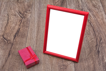 Picture frame with a gift on a wooden background