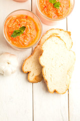 Tomato soup gazpacho, bread on white wooden background top view.