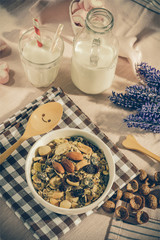 Breakfast set. mix oat granola in white bowl with pink heart sweet marshmallow on table set background, serve with white milk in glass and Bottle, top view, Healthy food concept, vintage tone color